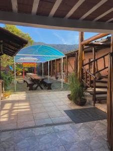 a patio with a picnic table and a blue umbrella at Chales Marissol in Ubatuba