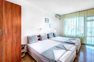 a bedroom with two beds and a large window at Guest House Zara in Primorsko