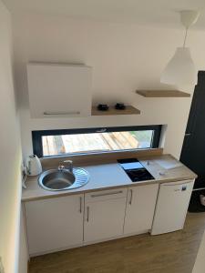 eine kleine Küche mit einem Waschbecken und einem Fenster in der Unterkunft Bursztynowy klif in Jastrzębia Góra