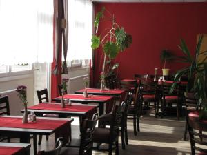 um restaurante com mesas e cadeiras numa sala com paredes vermelhas em Hotel Stadt Wittstock em Wittstock