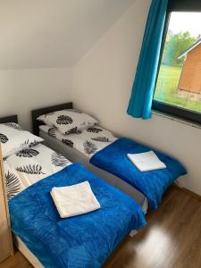 um quarto com duas camas com lençóis azuis e uma janela em Bursztynowy klif em Jastrzebia Gora