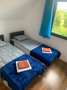a room with two beds with blue sheets and a window at Bursztynowy klif in Jastrzębia Góra
