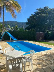 una mesa y sillas junto a una piscina en Chales Marissol, en Ubatuba