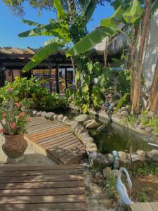 a wooden bridge over a pond in a garden at Chales Marissol in Ubatuba
