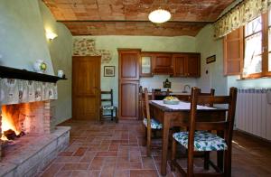 eine Küche mit einem Kamin sowie einem Tisch und Stühlen in der Unterkunft Agriturismo D' Epoca La Marianella in Catabbio