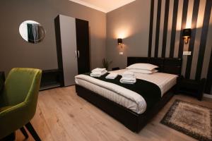een slaapkamer met een bed en een groene stoel bij Resita Residence in Reşiţa