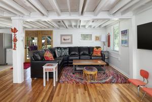 a living room with a black leather couch and a table at Folly Vacation 305 E Erie Fantastic Location in Folly Beach