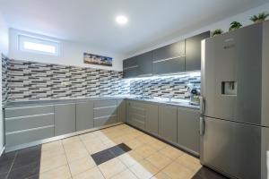 a large kitchen with gray cabinets and a refrigerator at Vila Jun in Eforie Nord