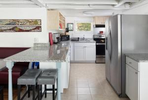 uma cozinha com um balcão com bancos e um frigorífico em Folly Vacation 305 E Erie Fantastic Location em Folly Beach