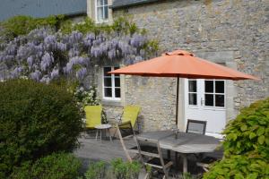 an orange umbrella and a wooden table and chairs at Les Chaufourniers/L'Etable in Crouay