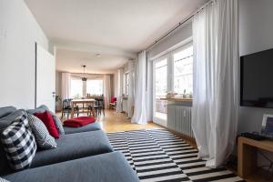 a living room with a blue couch and a television at WÄLDER: Quartier Titisee in Titisee-Neustadt