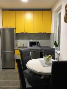 uma cozinha com armários amarelos, uma mesa e cadeiras em Sunce em Kruševac