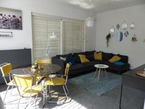a living room with a couch and a table and chairs at Flandriens in Bredene