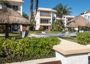 een resort met stoelen, rieten parasols en palmbomen bij Casa Frida in Puerto Morelos