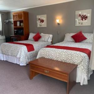 a bedroom with two beds with red and white sheets at Yankee Trail Motel in Holderness