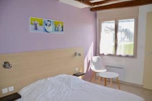 a bedroom with a bed and two chairs and a window at La petite maison 4 in Avoine