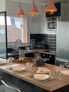 a kitchen with a table with plates and glasses on it at Duplex Fossorier - BALCON CENTRE VILLE - in Deauville +4 photos
