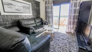 アルブフェイラにあるThe Ocean Apartment by Golden Zenithのリビングルーム(革張りのソファ、テレビ付)