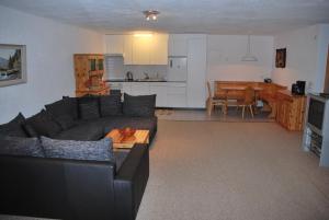a living room with a black couch and a kitchen at Moosalpe B Bürchen in Bürchen