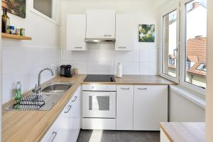 cocina con armarios blancos, fregadero y ventana en Helle und gemütliche Wohnung in zentraler Lage en Graz