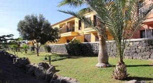 a palm tree in front of a yellow building at Residencial Atlantico I in Costa Del Silencio