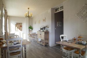 uma sala de jantar com mesas e cadeiras e uma cozinha em Les 4 saisons em Graye-sur-Mer