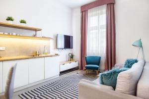 a living room with a couch and a chair and a kitchen at Cracow Rentals Zacisze in Kraków