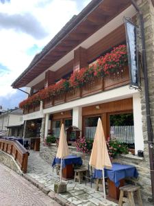 a building with tables and umbrellas in front of it at Hotel Capriolo in Madesimo