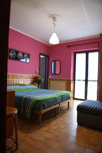 Hotel La Capannina في Massino Visconti: غرفة نوم بسرير وجدار وردي