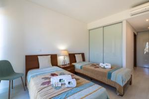 um quarto com duas camas e uma cadeira. em BmyGuest - Cavalo Preto Beach Apartment em Loulé