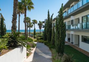 a walkway in front of a building with palm trees at BmyGuest - Cavalo Preto Beach Apartment in Loulé