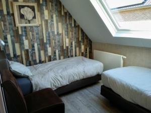 a bedroom with two beds and a sloped ceiling at B&B Hoeven Het Gehucht in Overpelt