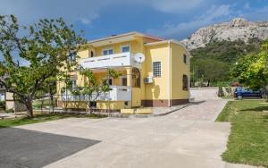 a yellow house with a mountain in the background at Apartments Polonijo in Baška