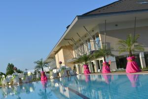 Dos mujeres vestidas de rosa están de pie en una piscina en Szépia Bio and Art Hotel, en Zsámbék