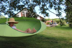 a woman sitting in a green pod hanging from a tree at Chambres & Gites les Pelaz in Hotonnes