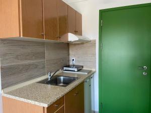 a kitchen with a sink and a green door at Marianna Sea View Afitos in Afitos