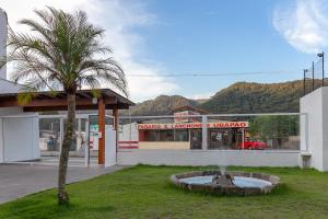 un palmier en face d'un bâtiment avec une fontaine dans l'établissement Sun Way Apartamentos com piscinas e churrasqueiras, à Ubatuba
