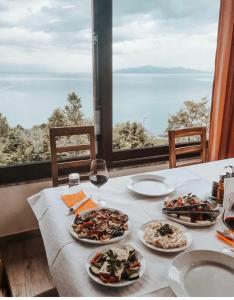 a table with three plates of food and wine glasses at Hotel Camping Lin in Pogradec