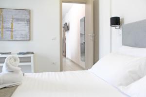 a white bedroom with two beds and a mirror at The AP Fiumaretta in Ameglia
