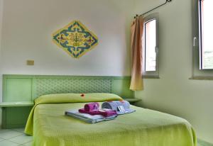 Un dormitorio con una cama verde con zapatos morados. en Casa Mare Cala Rossa, en Trinità dʼAgultu