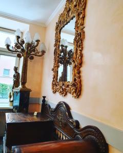 un miroir suspendu sur un mur à côté d'une chaise dans l'établissement Esos Hotel Quelle, à Bad Ragaz