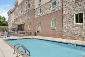una piscina di fronte a un edificio in mattoni di Candlewood Suites - Newnan - Atlanta SW by IHG a Newnan