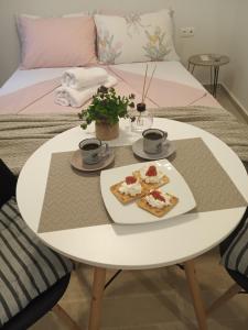 a white table with two plates of food on it at DORA'S APARTMENTS STUDIO 1 in Corfu Town