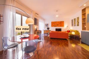 un soggiorno con tavolo, sedie e divano di Naima Sea View Design Apartment By HouseinNaples a Napoli