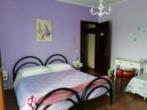 ein Schlafzimmer mit einem Bett, lila Wänden und einem Kronleuchter in der Unterkunft Cit Ni in Bosia