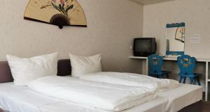 a bedroom with a bed with white sheets and blue chairs at China Restaurant Hotel Lotus in Rothenburg ob der Tauber