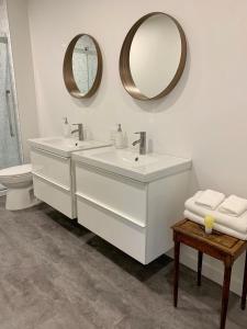 - une salle de bains blanche avec deux lavabos et un miroir dans l'établissement Appartements Gite Kezako, à Lévis