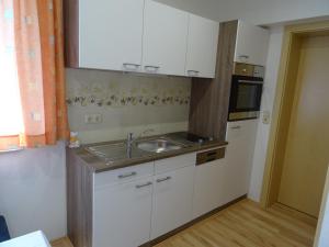 una cocina con armarios blancos y fregadero en Bauernhof Familie Tauber-Scheidl en Grossmeinharts