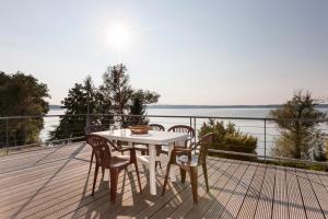 a table and chairs on a deck with a view of the water at Ferienhaus Malgosia direkt am See in Kruklanki
