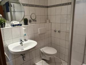 a white bathroom with a toilet and a sink at Olympia Hotel & Restaurant in Inden +21 photos